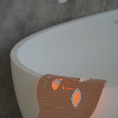 NursesChoice LED face mask lit and resting over the edge of a bath, stocked at The Glow Co. Aesthetics Gordon Park Brisbane