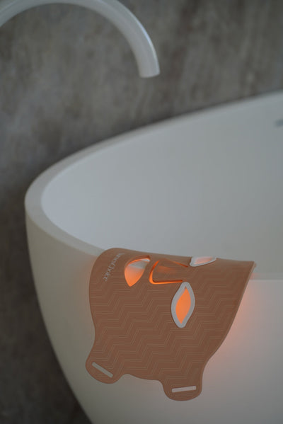 NursesChoice LED face mask lit and resting over the edge of a bath, stocked at The Glow Co. Aesthetics Gordon Park Brisbane